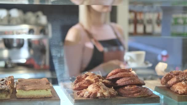 Fresh pastries in the confectionery store. Close-up products with saleswoman on a background - 映像、動画