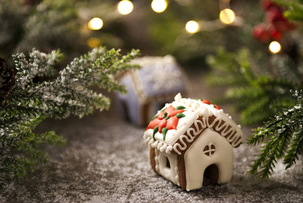 Casas de pan de jengibre con glaseado blanco y azul y rama de árbol de Navidad con conos de abeto cubiertos de nieve
  - Foto, imagen