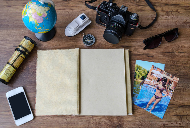 Kladblok, creditcards, paspoort, ticket, camera, telefoon en kompas op een houten achtergrond - Foto, afbeelding
