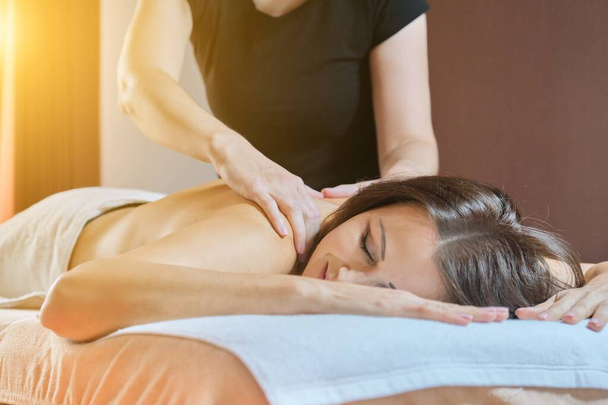 Adult mature woman resting on back massage procedure on massage table in beauty salon - Фото, изображение