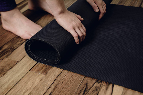 Close-up of young woman rolling her fitness mat - Φωτογραφία, εικόνα