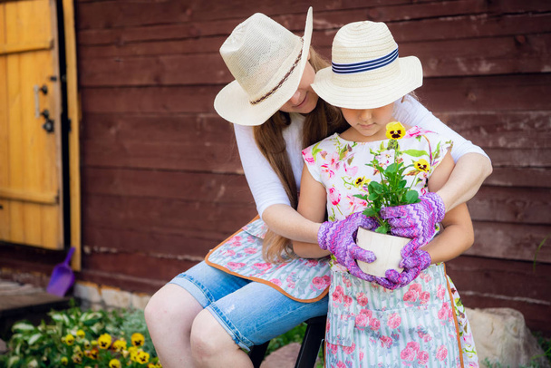 Gärtnern, Pflanzen - Mutter mit Tochter pflanzt Blumen in den Blumentopf - Foto, Bild