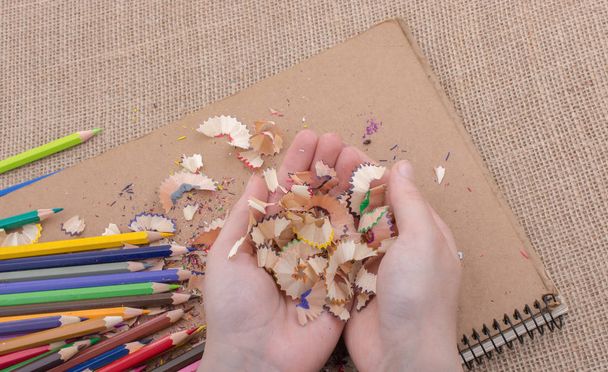 Colorful pencil shavings in hand on a notebook - Fotografie, Obrázek