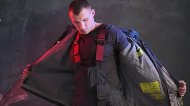Moedige brandweerman draagt uniform terwijl hij tegen een grijze muur staat - Video