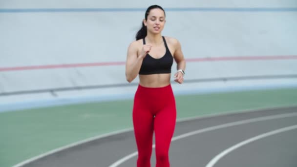 Mujer entrenando en ropa deportiva en pista de atletismo. Chica de fitness cansado corriendo
 - Imágenes, Vídeo