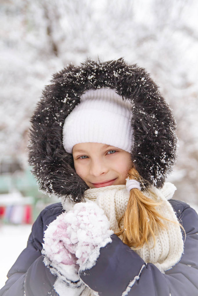 Happy child girl playing on a winter walk in nature with snow - Fotó, kép