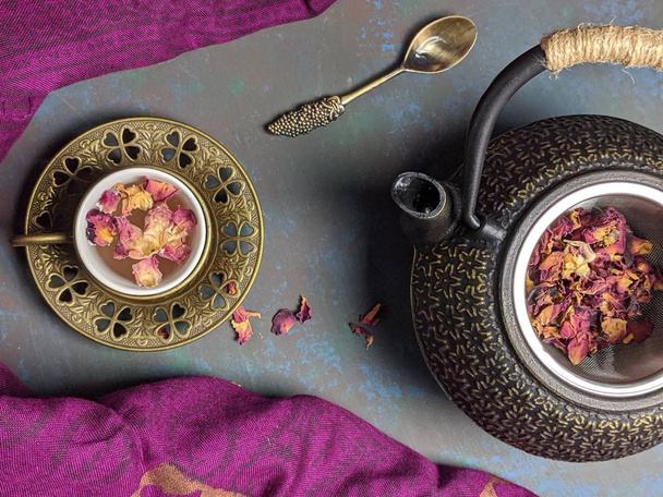 Uma xícara de chá de rosa com uma panela de chá de metal
. - Foto, Imagem