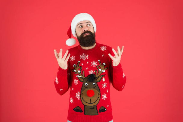 Winter holidays. Man bearded hipster wear winter knitted hat. Barbershop facial hair. Winter fashion. Guy wearing winter clothes accessory. Bearded Santa claus red background. Something on his mind - Fotoğraf, Görsel