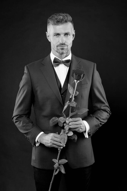 Romantic gentleman. Man mature confident macho with romantic gift. Handsome guy rose flower romantic date. Well groomed macho tailored suit. Make good first impression. Valentines day and anniversary - Fotografie, Obrázek