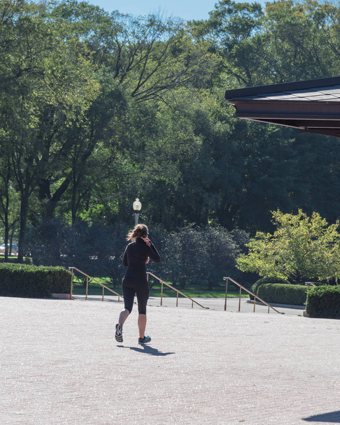 Şehir parkında çalışan sonbahar spor sağlıklı kadın geri görünümü. Chicago şehir merkezinde gündüz kulaklık egzersiz ile Sağlıklı kadın - Fotoğraf, Görsel