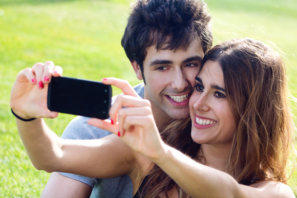 happy young couple with smartphone at the park - 写真・画像