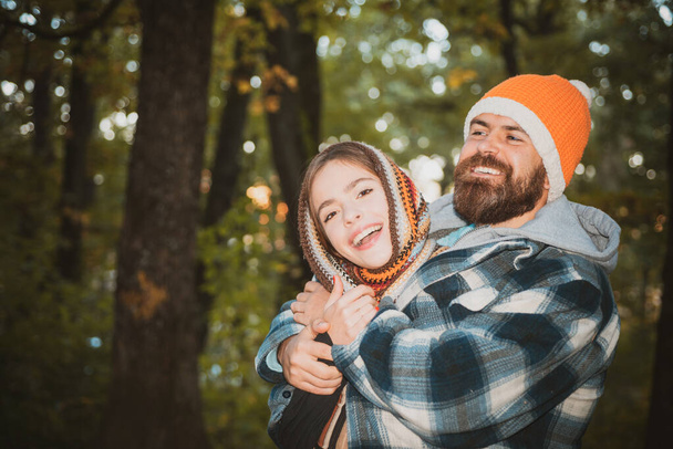 Cozy mood and autumn inspiration concept. Happy smiling and hugging couple in warm knitted hat and scarf walking outdoor in autumn forest. Fall yellow trees background. - Фото, изображение
