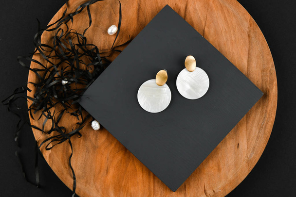 Round white earrings. Close-up. Golden latch. Laid out on a wooden stand. View from above. The concept of jewelry and jewelry. Gifts for women. shopping - Photo, Image