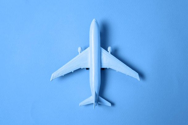 Just flat lay design toy plane colored in trendy color of year 2020 Classic Blue background. Яркий макроцвет 19-4052. Travel by plane trip ticket tour concept
 - Фото, изображение