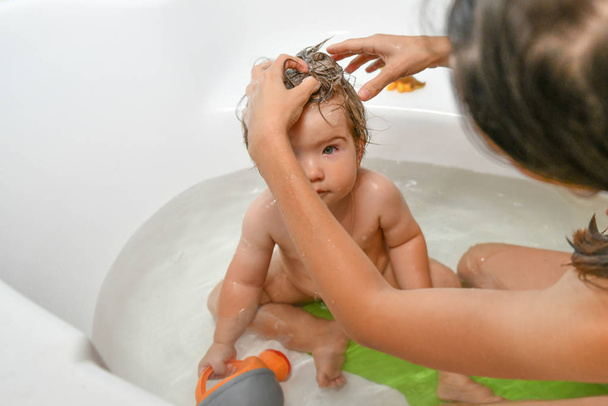 A mãe lava a cabeça dos bebés. Bebê banho conjunto e mãe. Um símbolo de limpeza e educação em higiene
. - Foto, Imagem