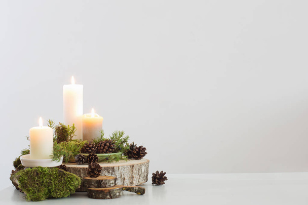burning candles on saw with cones and branches on white backgrou - Foto, Imagem