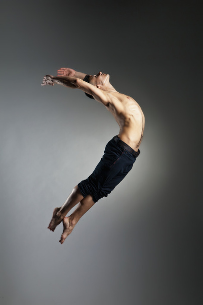 Caucasian man gymnastic leap posture on grey - 写真・画像