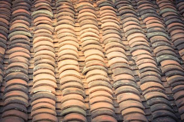 Ročník tón zakřivené hliněné dlaždice střechy v různých barvách ze starého domu v severním Vietnamu, pozdní odpoledne světlo. Starověký, ošlehaný povrch střechy, mechová textura. Přírodní bezešvé vzor pozadí - Fotografie, Obrázek