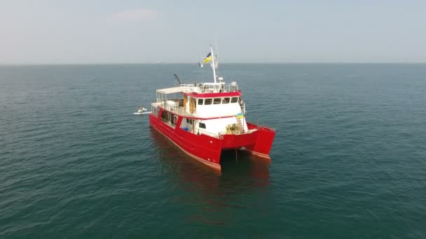 Výzkumná loď pluje uprostřed oceánu a moře. Červený katamarán pod ukrajinskou vlajkou - Záběry, video