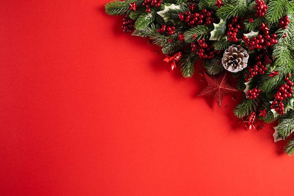 Karácsonyi háttérkoncepció. Top view karácsonyi ajándék doboz piros golyók lucfenyő ágak, fenyőtoboz, piros bogyó csillag és harang piros háttér. - Fotó, kép