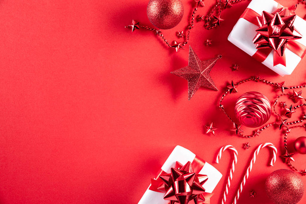 Концепция Рождества. Вид сверху рождественской подарочной коробки красный и золотой шар со снежинками на светло-красном фоне. - Фото, изображение
