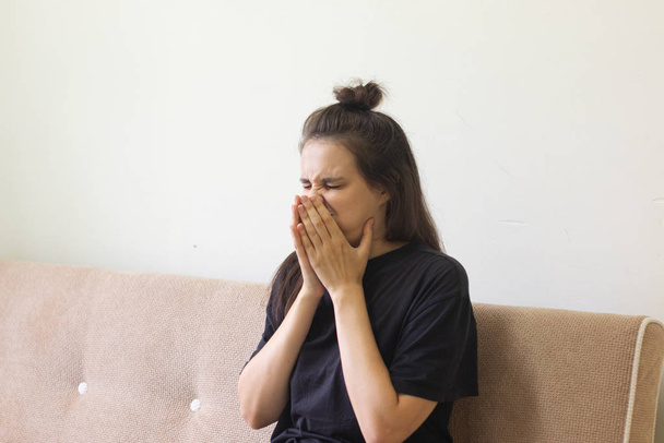 Sick young woman sitting at home with a runny nose. - 写真・画像