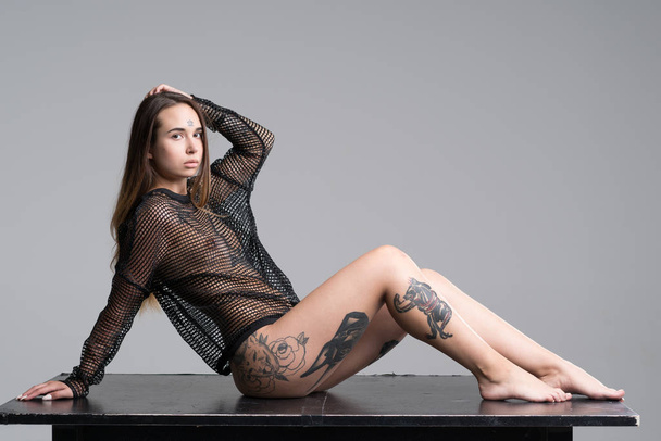νέος όμορφο κορίτσι με τατουάζ πόζα γυμνό στο στούντιο - Φωτογραφία, εικόνα