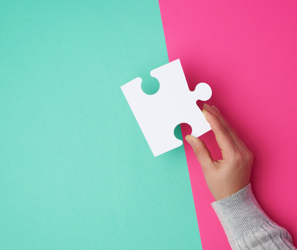 female hand holds a big empty white puzzle over a colorful backg - Fotoğraf, Görsel
