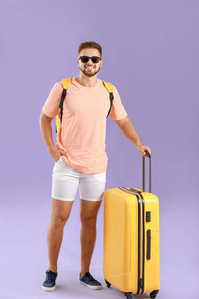 Young male tourist with luggage on color background - Foto, immagini