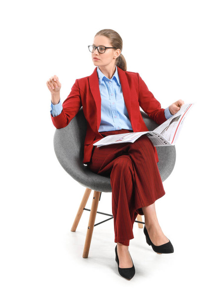 Young businesswoman with newspaper sitting in armchair against white background - Foto, immagini