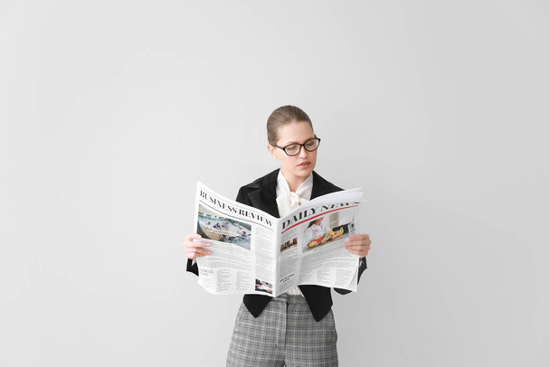 Joven empresaria con periódico sobre fondo claro
 - Foto, Imagen