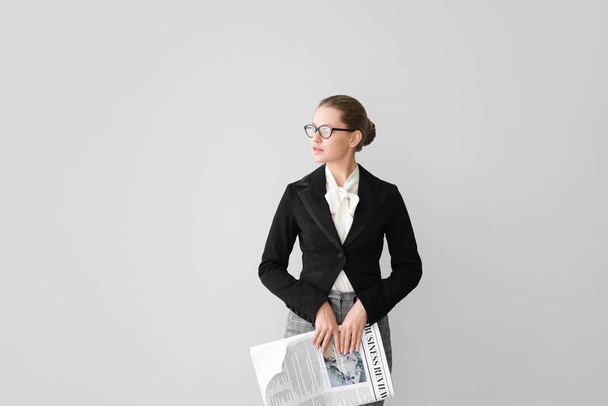 Young businesswoman with newspaper on light background - Photo, image
