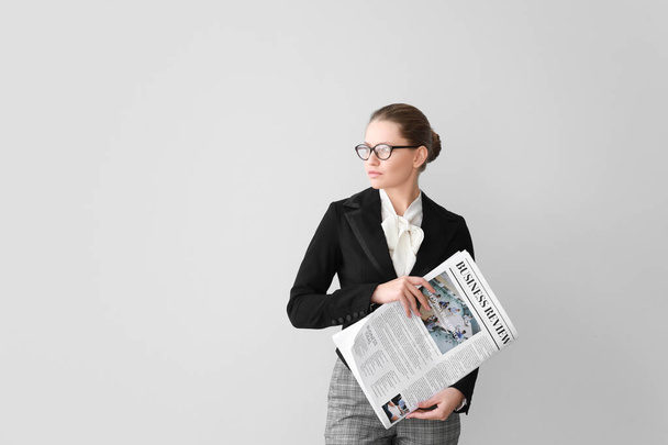 Young businesswoman with newspaper on light background - Φωτογραφία, εικόνα