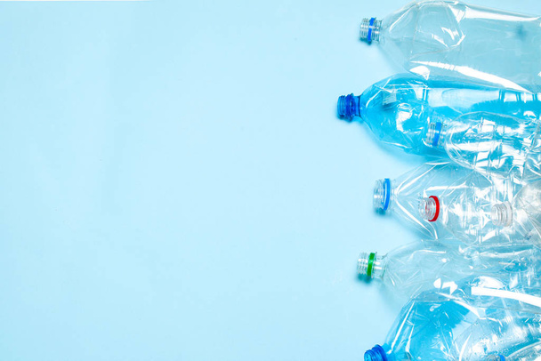 Crumpled plastic bottles on a blue background. Plastic trash. Copy space for text. - Фото, изображение