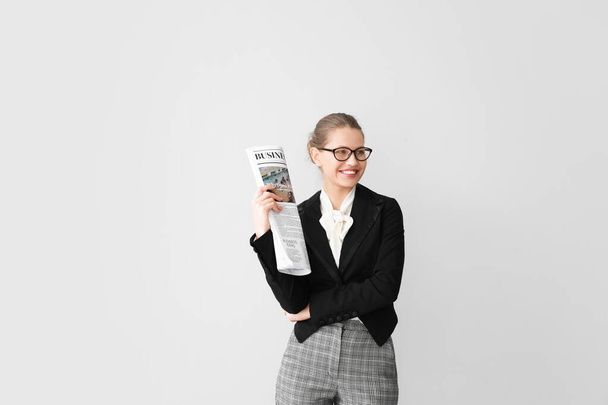 Young businesswoman with newspaper on light background - Foto, imagen