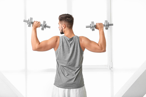 Sporty young man training with dumbbells in gym - Foto, Imagem