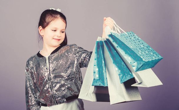 Sale discount. Shopping day. Child hold bunch packages. Kids fashion. Birthday girl. Surprise gift. Girl with shopping bags violet background. Shopping and purchase. Get better looking. Black friday - Zdjęcie, obraz