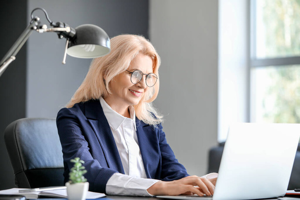 Femme d'affaires mature travaillant sur un ordinateur portable au bureau
 - Photo, image