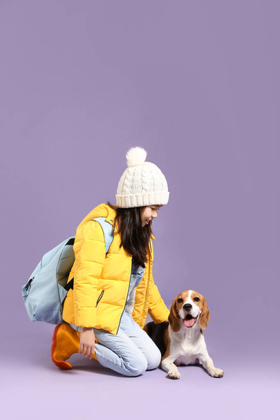 Little Asian girl with cute beagle dog on color background - Фото, изображение