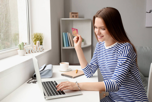 Young woman with credit card and computer shopping online at home - Foto, Imagem