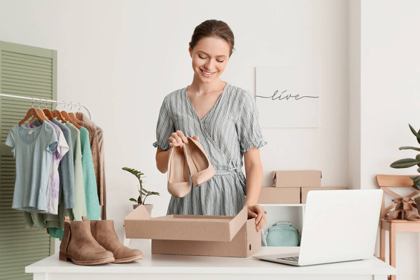 Young woman preparing parcel for client in office - Foto, Imagem