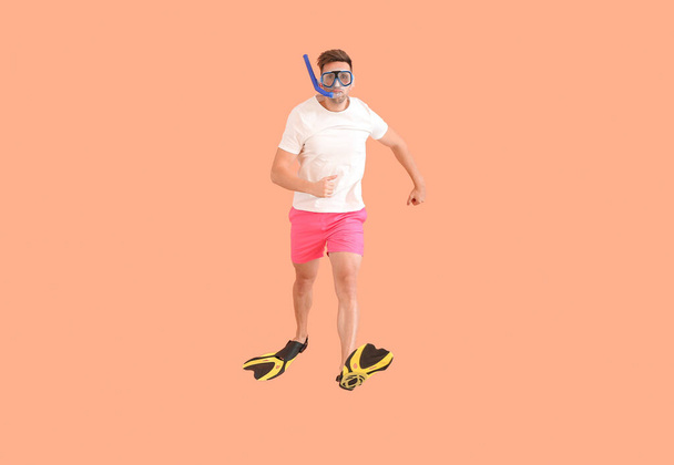 Jumping man in paddles and snorkeling mask on color background - Valokuva, kuva