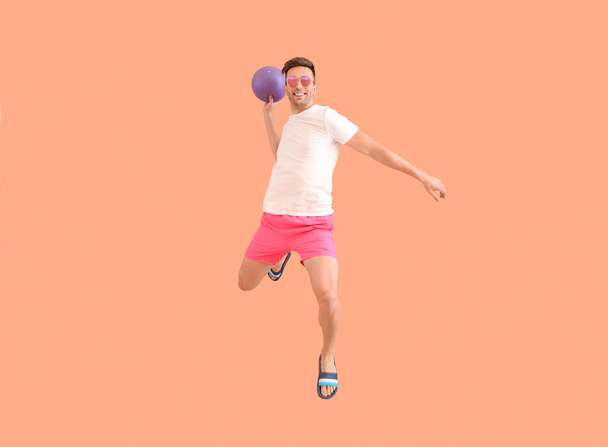 Jumping young man with ball on color background - Fotoğraf, Görsel
