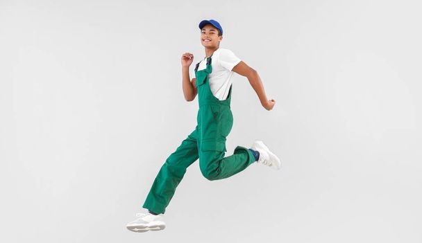Saltando menino adolescente afro-americano em uniforme no fundo branco
 - Foto, Imagem