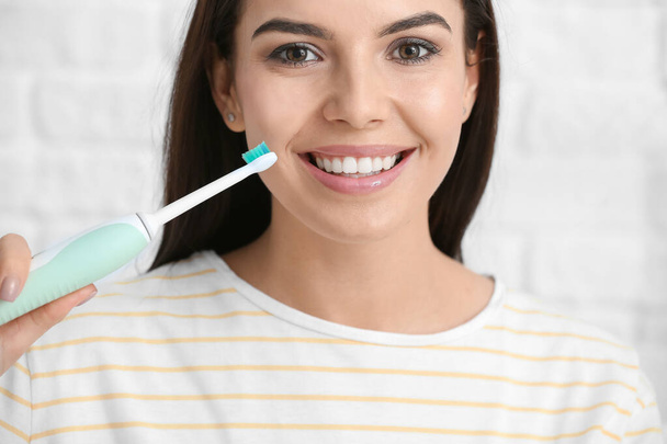 Beautiful young woman with tooth brush on light background - Фото, изображение