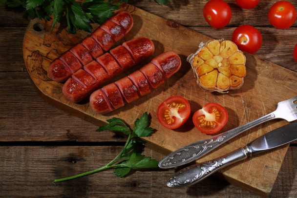 fried sausages with vegetables on a wooden table - Fotografie, Obrázek