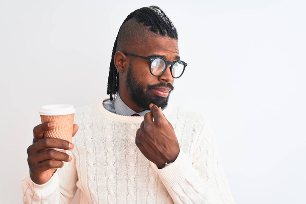 Afro-Amerikaanse man met vlechten drinken take away koffie over geïsoleerde witte achtergrond serieus gezicht denken over vraag, zeer verward idee - Foto, afbeelding