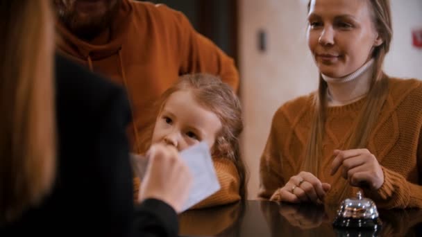 Rodinné odbavení v hotelu - žena na recepci vysvětlí rodině jejich privilegia v hotelu a dá jim prospekt a klíče - Záběry, video
