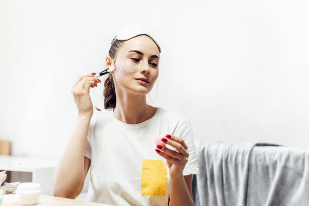 Beautiful female applying cosmetics on her face. - Zdjęcie, obraz