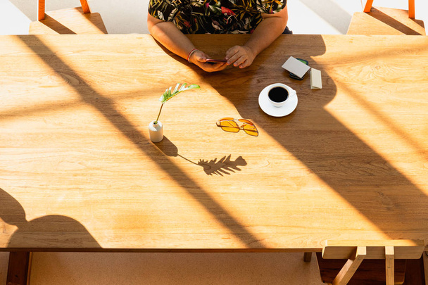 Vista dall'alto della mano utilizzando il telefono cellulare con tazza di caffè sul tavolo in legno nel caffè
. - Foto, immagini